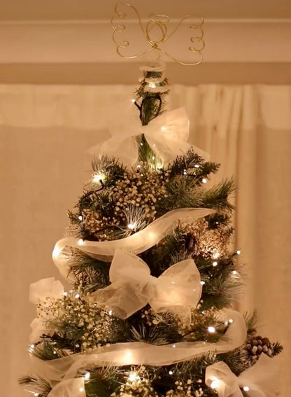 A Christmas tree dressed with warm white lights, tulle and a handmade Angel tree topper made with gold wire and cream knitted yarn