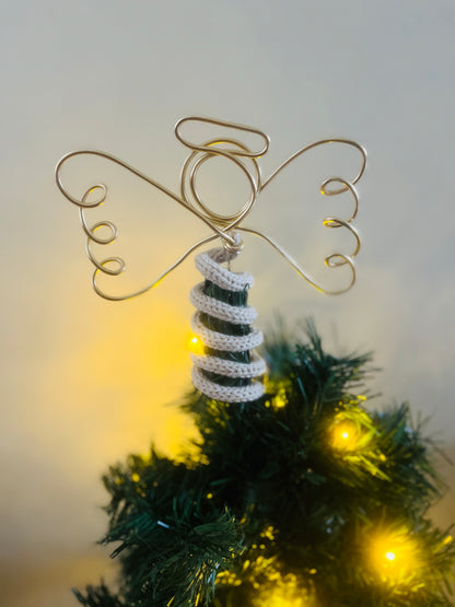A handmade wire angel tree topper on top of of a Christmas tree