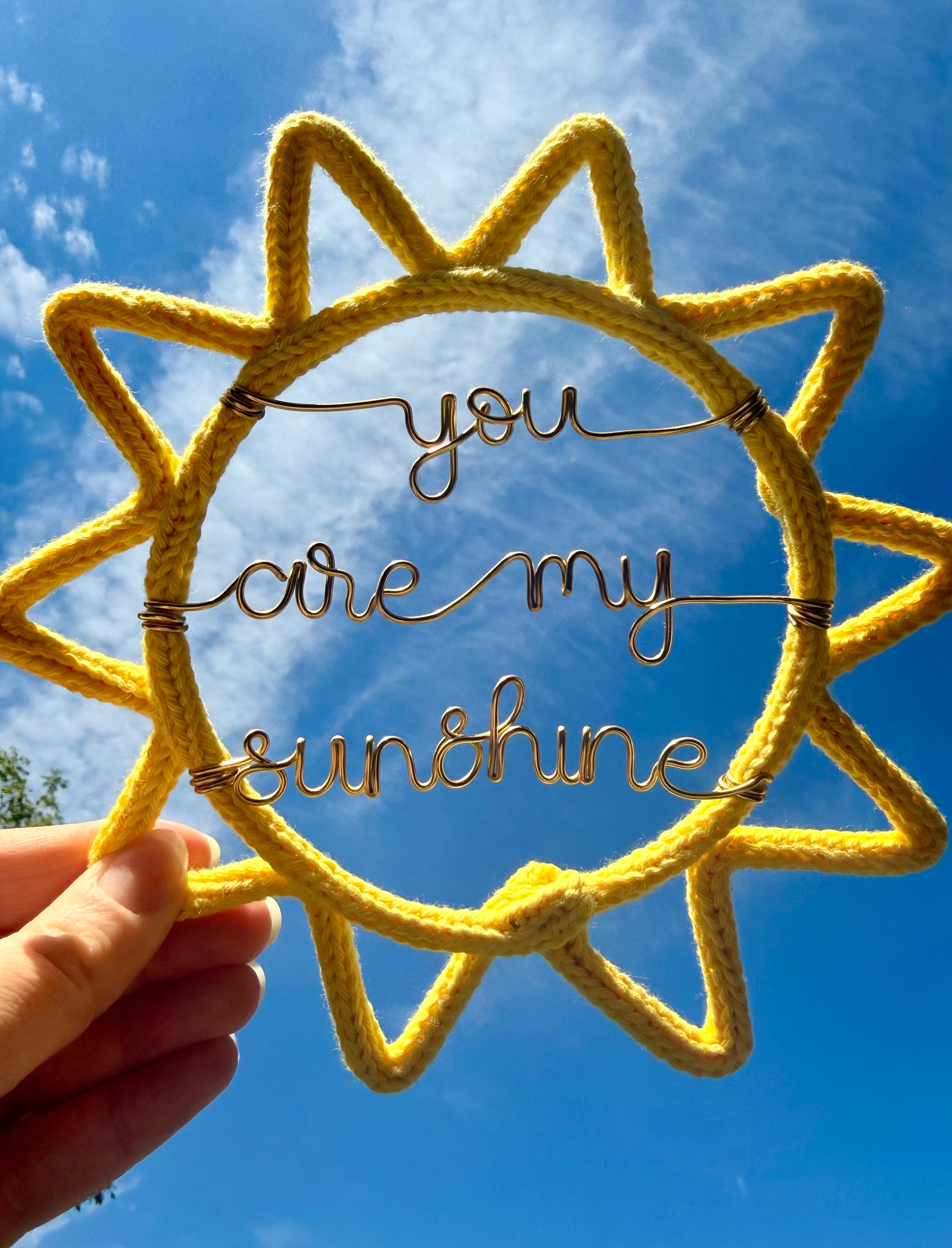 Sun-shaped yellow frame with 'you are my sunshine' text against a blue sky.